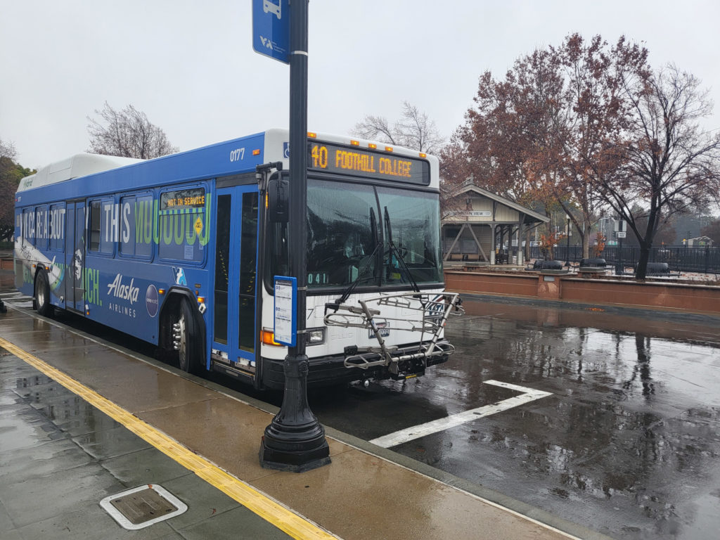VTA hybrid bus 0177 on break from the 40 bus line at Mountain View Transit Center, in the rain. Bus is parked in the Transit Center's bus lane while the driver is on break. Bus is wrapped in an ad for Alaska Airlines.